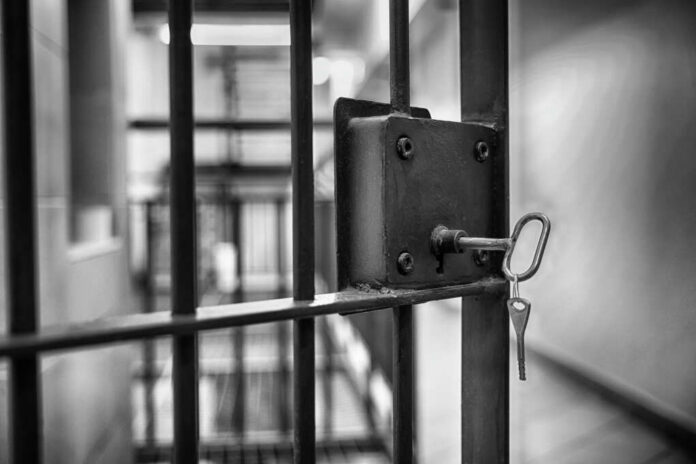 Close-up of a jail cell lock with a key hanging