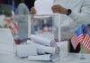 Election Night Ends, Ballots Keep Coming Person casting a vote into a transparent ballot box during an election