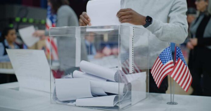 Person casting a vote into a transparent ballot box during an election