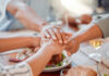 New Bill Lets Outsiders Call The Shots? Several hands stacked together over a plate of food, symbolizing unity and support