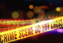Shoplifting Call, Infant Dead—Town Erupts Yellow police tape marking a crime scene with blurred lights in the background