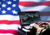 Laptop with surveillance software against a blurred American flag