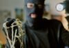 masked person holding jewelry and pearls