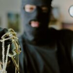 masked person holding jewelry and pearls