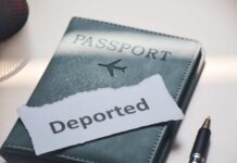 A passport with a note that reads 'Deported' placed beside a pen