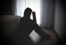 Billionaire Mogul Accused — Victims Speak Out A silhouette of a woman sitting on the floor, appearing contemplative and distressed