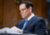 Individual in a suit reviewing documents during a senate hearing