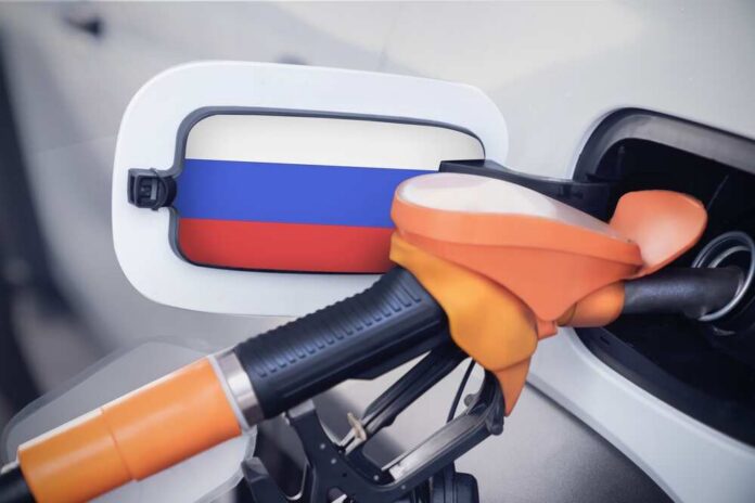 The,Russia,Flag,On,The,Lid,Of,The,Gas,Tank Fuel nozzle inserted into a car with a flag-themed fuel door