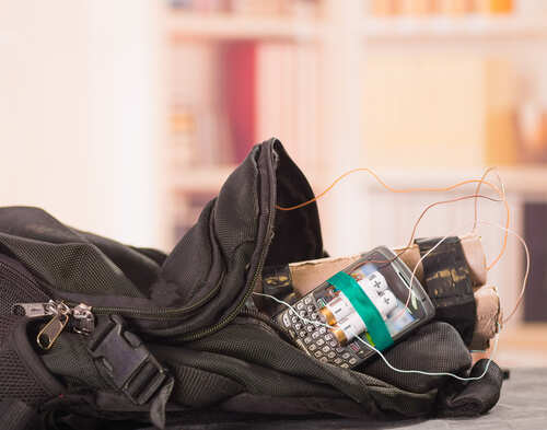 Close,Up,Shot,Of,Improvised,Explosive,Device,Bomb A backpack containing a mobile phone and wires, suggesting a suspicious setup