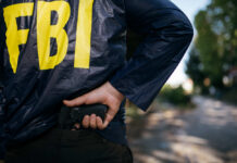 FBI agent gripping handgun near waistband outdoors