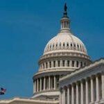DOJ Nominee Faces Tough Hearing United States Capitol dome with American flags against a blue sky