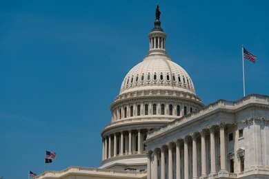 2645778901 United States Capitol dome with American flags against a blue sky