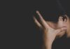NYU Firestorm Over ‘Suicidal Empathy’ person covering face with hand in dark background