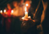 Inside Iran’s Farewell For Khamenei People holding lit candles in a dimly lit setting