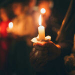 Inside Iran’s Farewell For Khamenei People holding lit candles in a dimly lit setting