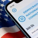 Mobile phone displaying Democratic National Committee website on an American flag background