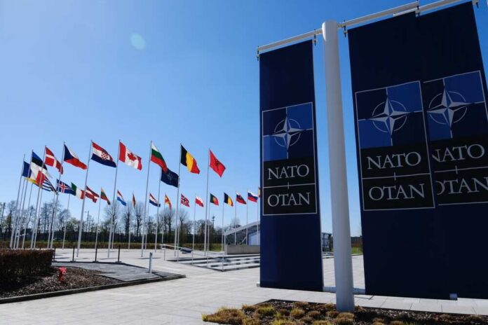 The,National,Flags,Of,Countries,Member,Of,The,Nato,Fly Flags of various nations displayed outside NATO headquarters under a clear blue sky