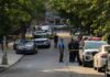 Police officers secure a residential street with patrol cars and yellow tape