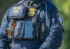 Family Seeks Answers After ICE Shooting Police officer in tactical vest with equipment and radio