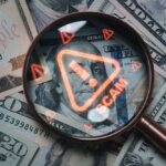 Investigators Trace Scams To U.S. Tech Magnifying glass over U.S. dollar bills with a scam warning