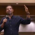 Legal Fight Gives Way To Scandal A speaker addressing an audience with a microphone in hand
