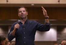 Legal Fight Gives Way To Scandal A speaker addressing an audience with a microphone in hand