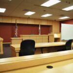 Clerk Stops Explosive Ambush Plot Interior view of an empty courtroom with wooden furniture and American flags