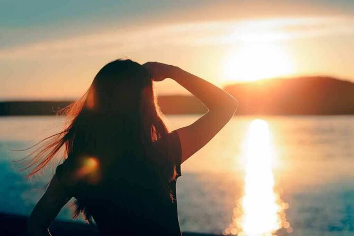 Silhouette of a person looking at a sunset over water