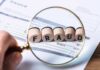 Magnifying glass highlighting wooden blocks spelling fraud on an invoice