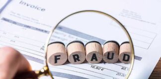 Magnifying glass highlighting wooden blocks spelling fraud on an invoice