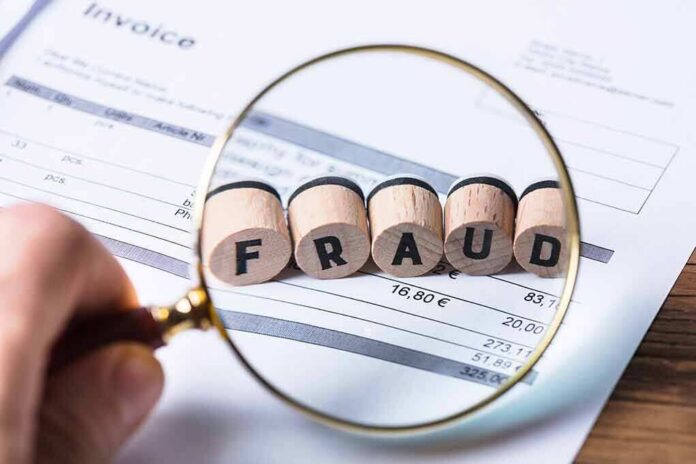 Magnifying glass highlighting wooden blocks spelling fraud on an invoice