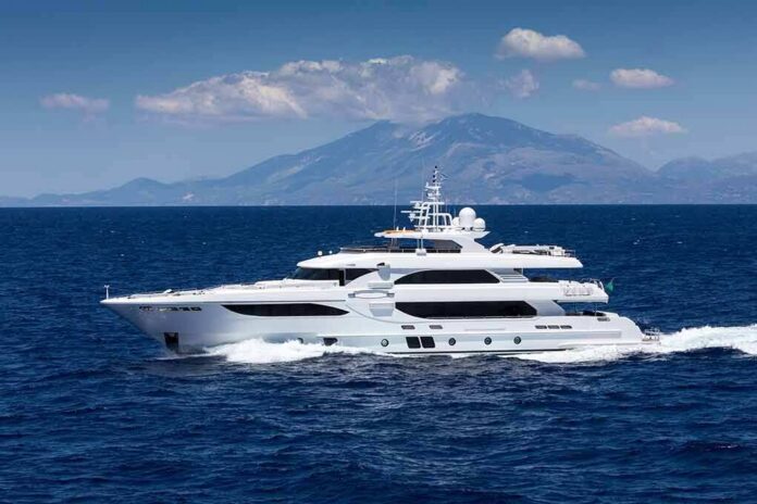 shutterstock_1057258229 Luxury motor yacht cruising on blue sea with mountains in background