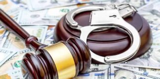 Judge's gavel and handcuffs on pile of US dollar bills