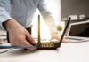 Invisible Tracking Baked Into Wi‑Fi Person plugging ethernet cable into Wi‑Fi router