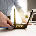 Person plugging ethernet cable into Wi‑Fi router