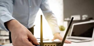 Person plugging ethernet cable into Wi‑Fi router