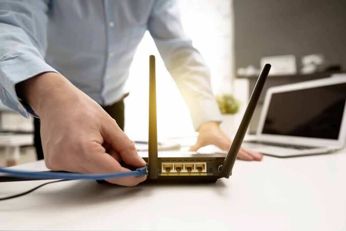 shutterstock_1320531272 Person plugging ethernet cable into Wi‑Fi router