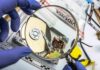 Forensic technician examining an open hard drive with a magnifying glass