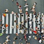 Crowd of pedestrians crossing a zebra crosswalk from above