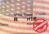 Six-Figure Visa Toll Roars Back H1B visa document with U.S. flag overlay and red Approved stamp