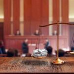 brass balance scale with files and gavel in a courtroom