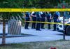 police officers stand behind caution tape at a park scene