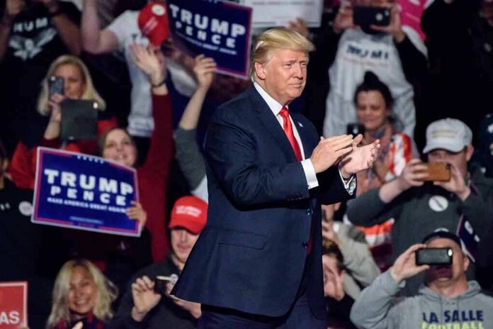 shutterstock_617079032 man in suit claps on stage at a rally