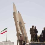 Iran Bounty Puts U.S. Troops in Crosshairs soldiers stand beside large missiles at outdoor display