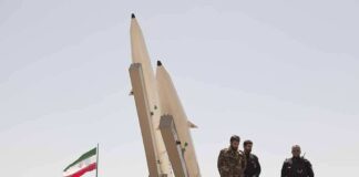 soldiers stand beside large missiles at outdoor display