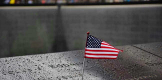American flag on a rainy memorial nameplate.