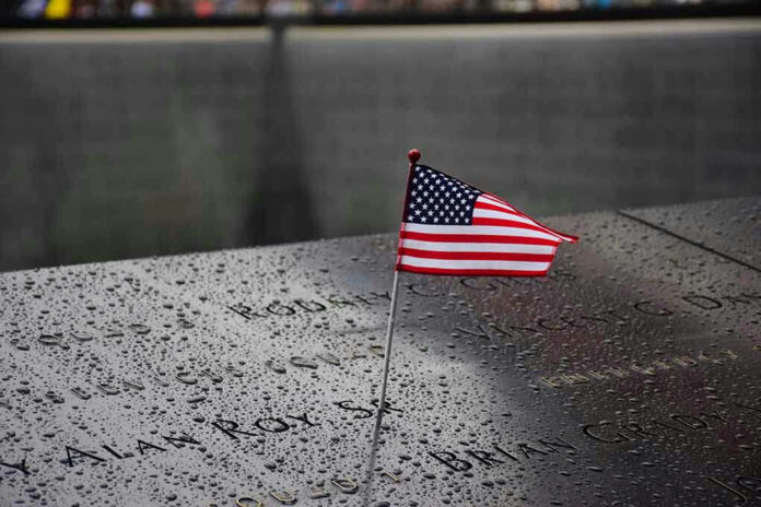 574569265 American flag on a rainy memorial nameplate.