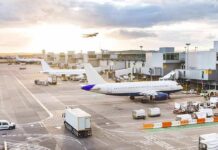 Airplanes at airport gates during sunset with ground vehicles and jet bridges
