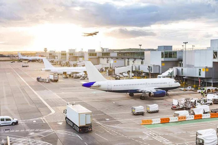 Airplanes at airport gates during sunset with ground vehicles and jet bridges