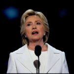 Clinton’s NYC Intern Gig: Hush, No Pay woman in white suit speaking at a microphone
